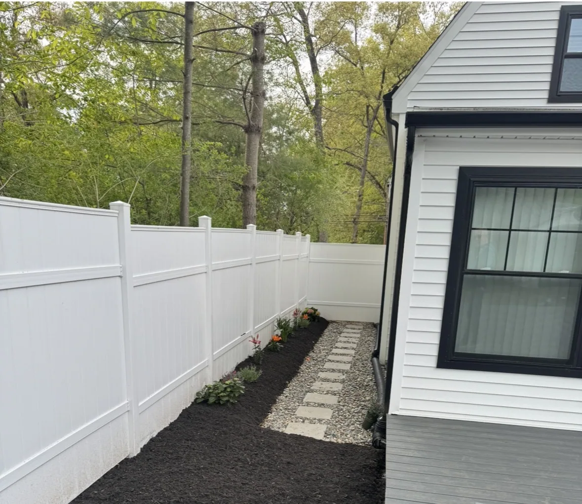 After: finished walkway, mulch and flowers beside white fence